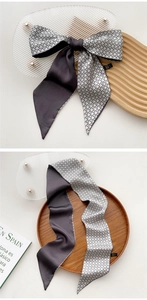Macro detail of a narrow two-sided silk scarf with geometric patterns and solid grey finish