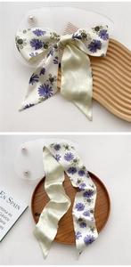 Detail view of a long satin scarf with yellow daisy print and stylish knotted bow design