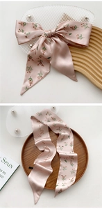 Detail of pink satin skinny scarf with delicate red floral print and elegant script lettering