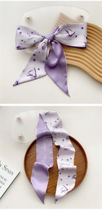 Detailed view of a purple silk scarf with floral print and handwritten typography art