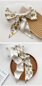 Detail of floral silk twilly scarf with yellow flowers and elegant script lettering