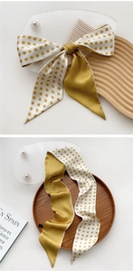 Detail of Mustard Yellow and polka dot silk scarf displayed on elegant wooden props