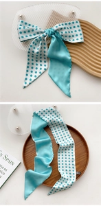 Detail of teal blue polka dot silk scarf tied in a bow on a wooden tray with acrylic plate