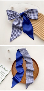 Detail of royal blue and gingham checkered silk scarf tied in a bow on a wooden tray