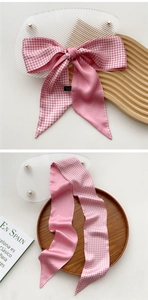 Detailed view of pink and white checkered skinny silk scarf tied in a bow