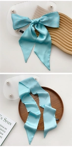 Detail of light blue silk scarf with split solid and plaid pattern on wooden tray