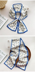 Detail of floral skinny silk scarf on wooden tray with lavender pattern and blue borders