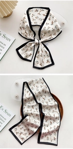 Detail of floral skinny silk scarf with black contrast borders in bow and hanging styles