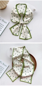 Close-up of cream skinny silk scarf with green clover print and contrasting edges