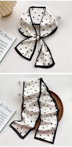 Detail of long floral twilly scarf with black clover pattern on white silk surface
