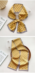 Detailed view of long yellow silk scarf with geometric monogram patterns and grey border