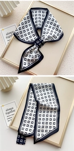 Dettaglio elegante foulard di seta bianco e nero con motivi geometrici e nodo a fiocco
