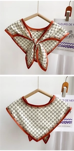 Close-up of beige silk scarf with letter D pattern and contrasting orange border