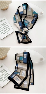 Close-up of a long narrow silk scarf featuring a geometric color block design in navy blue