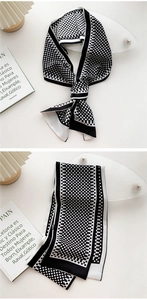 Detailed view of polka dot silk scarf tied on stand and folded on a book