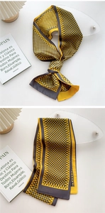 Detail of yellow silk-like skinny scarf with grey polka dots on a minimalist background