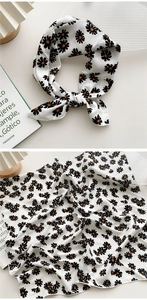 Détail d'un foulard en coton lin blanc à imprimé pâquerettes, noué et posé à plat