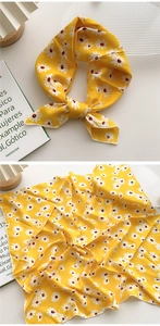 Détail d'un foulard en soie jaune avec motif de marguerites et bordure cousue fine