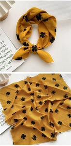 Détail d'un foulard en soie jaune gingembre avec motif trèfle et bordure cousue