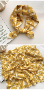 Détail macro d'un foulard carré jaune à fleurs avec bordure soignée et texture douce en coton