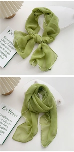 Detail of light green silk scarf with delicate white wavy embroidered edge stitching