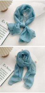 Detail of light blue silk scarf with white wavy embroidered edges and soft texture