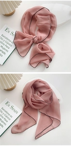 Detail of pink chiffon scarf with black wavy edges showing knots and silk texture
