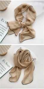 Detail of khaki silk scarf with black stitched edges shown in a lifestyle setting