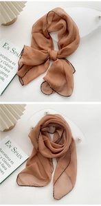 Detail of caramel silk scarf with black wavy edges showing knots and elegant draping
