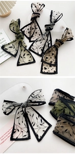 Detailed view of floral mesh skinny scarves with black hem and elegant leaf print patterns