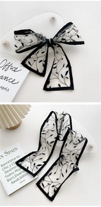 Detail of sheer black floral organza ribbon tied as a bow and laid flat on a desk