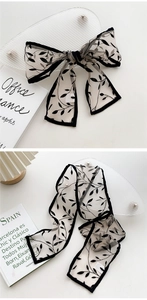 Close-up of lightweight sheer mesh scarf with black leaf print and delicate piped edges