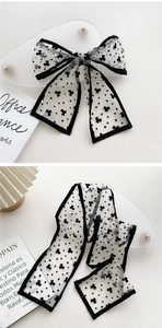 Close-up of elegant black and white polka dot mesh scarf tied in a bow on a white desk