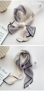 Detail of elegant two-tone long silk scarf with black stitched edges and chiffon texture