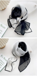 Detail of elegant black and white long silk scarf with semi-transparent texture on a tray