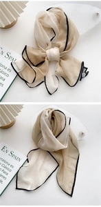 Detailed view of lightweight spliced silk scarf in beige and cream with black trim