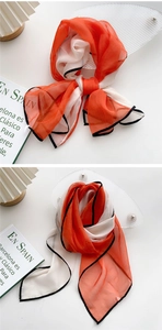 Detail of color-block silk scarf in orange and white with black stitched edges