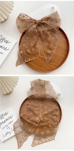Detailed view of a brown lace skinny scarf featuring floral embroidery and wavy edges