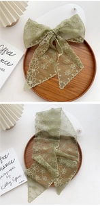 Detail of dark green lace scarf with white floral embroidery and neat stitched edges