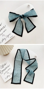 Close-up of light blue polka dot silk scarf tied in a bow with elegant black trim