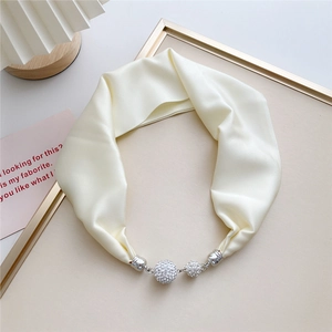 Detail of cream silk scarf with rhinestone magnetic spheres on a gold-rimmed tray