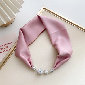 Macro detail of lotus pink silk scarf with a sparkling rhinestone magnetic buckle