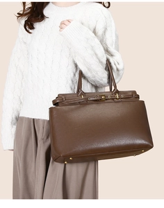 Dettaglio borsa tote in pelle marrone con fibbia dorata e piedini protettivi