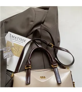 Detail of glossy beige Boston bag with brown straps and elegant gold hardware