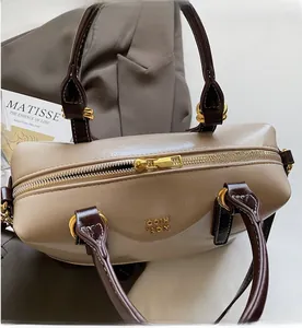 Close-up of beige Boston bag with smooth gold zipper and contrasting brown handles