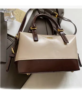 Close-up of contrast beige and brown Boston bag with golden hardware on a stylish desk