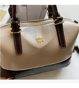 Close-up of litchi texture leather and golden metal logo on the two-tone Boston bag