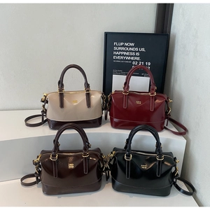 Group display of high-shine leather boston bags in four colors with gold logo detail