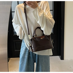 Detail of a dark brown leather Boston bag showing golden hardware and MIOO BAG logo
