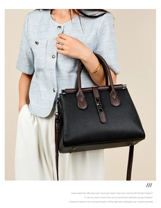 Detail of black lychee grain leather tote bag with brown handles and metal buckle clasp